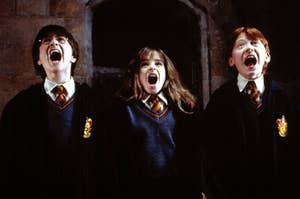 Daniel Radcliffe, Emma Watson, and Rupert Grint, in Hogwarts robes, screaming in a scene from Harry Potter