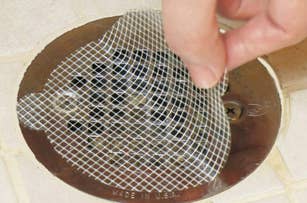 Hand lifting a mesh drain cover from a floor drain