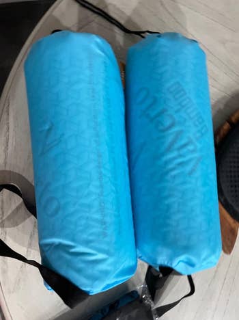 Two blue Vango camping sleeping bags on a table with straps attached