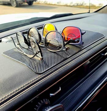 Sunglasses with different lens tints displayed on a car dashboard mat