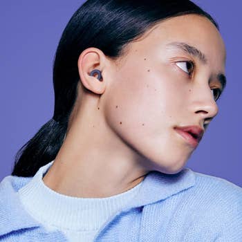 Person wearing wireless earbuds looks to the side, showcasing a sleek design for a shopping article