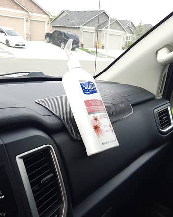 Bottle of Suave Wild Cherry Blossom body lotion on a car dashboard, secured with a non-slip mat