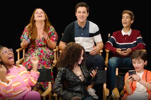 the "Wizards Beyond Waverly Place" cast sitting in two rows, holding phones and reacting expressively