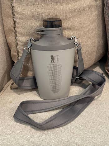 Reusable water bottle with a shoulder strap, featuring a minimalist design