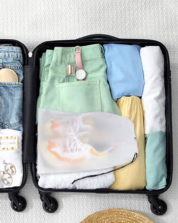 Neatly packed suitcase with folded clothes, a watch, and sneakers. Ideal for a stylish, organized trip