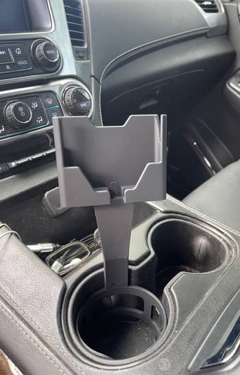 Phone holder attached to a car cup holder, situated in the vehicle's center console