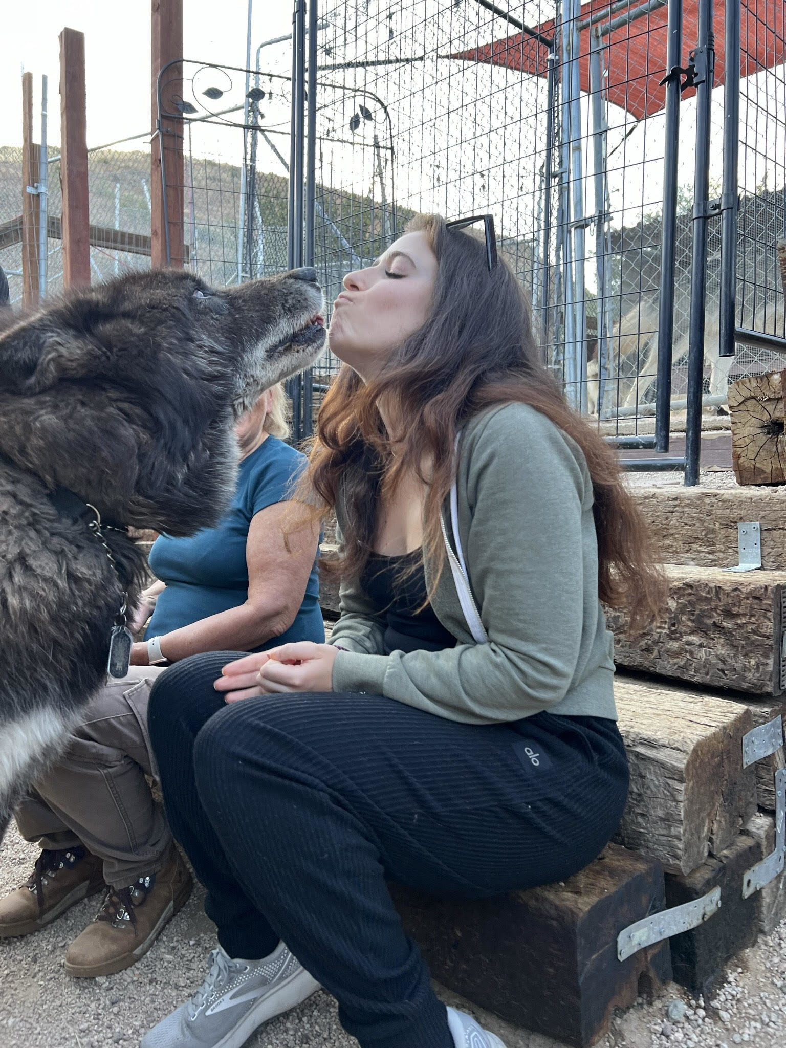 A seated woman with a wolf very close to her raised face