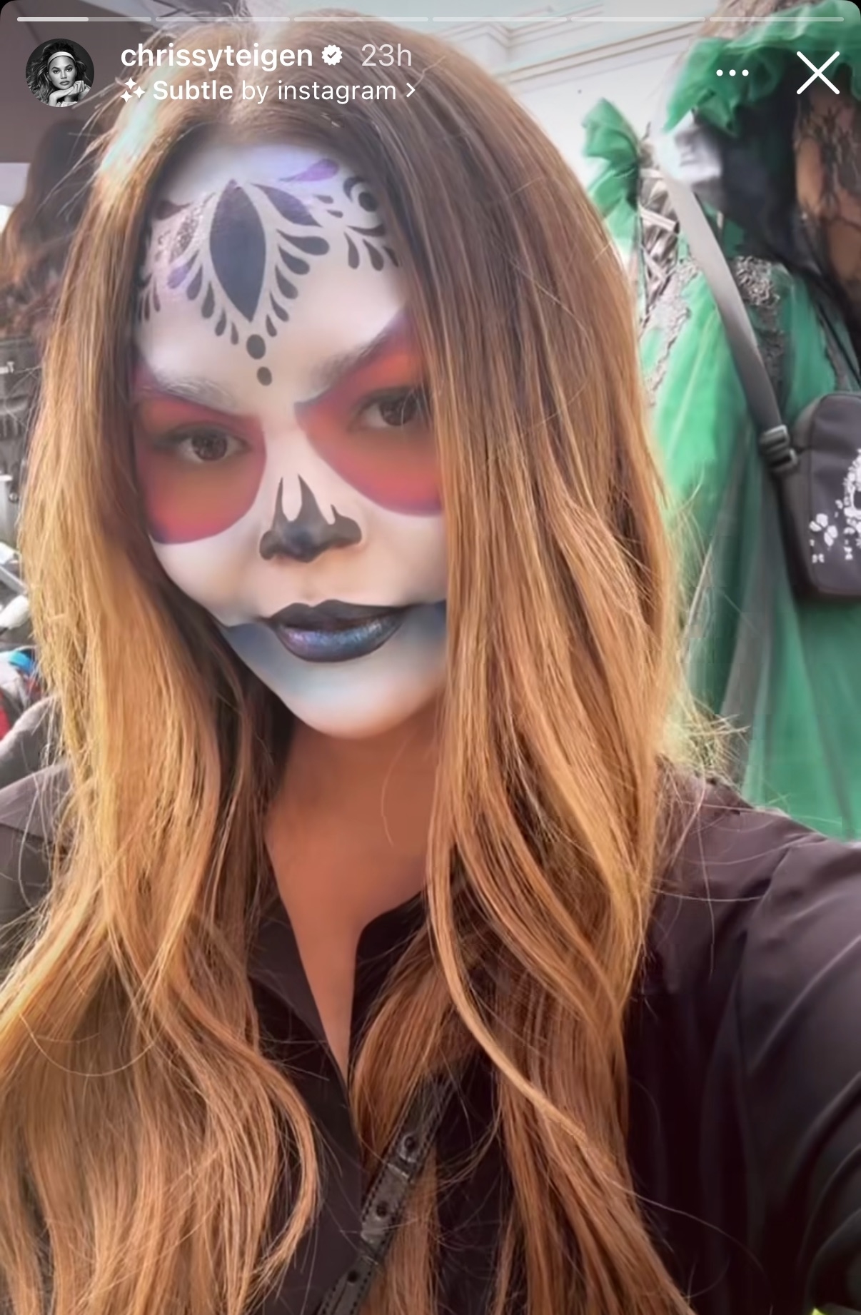 Chrissy Teigen with long hair and intricate face paint at a Day of the Dead celebration