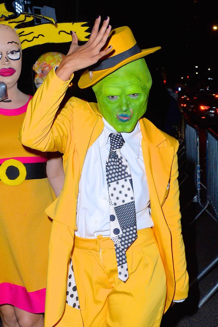 Janelle Monáe dressed as the Mask, wearing a yellow suit and hat with a polka dot tie, poses at a nighttime event