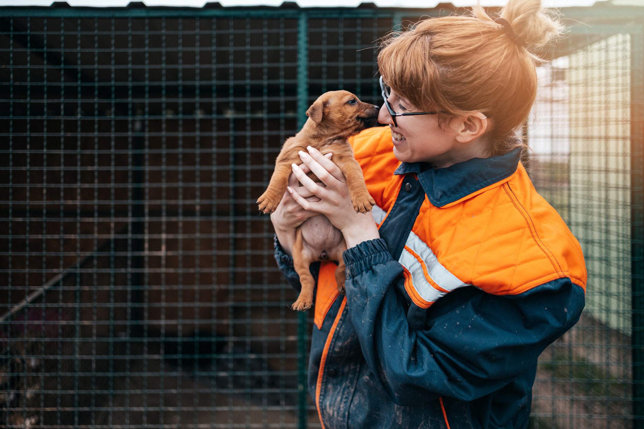 A woman snuggling and holding a puppy