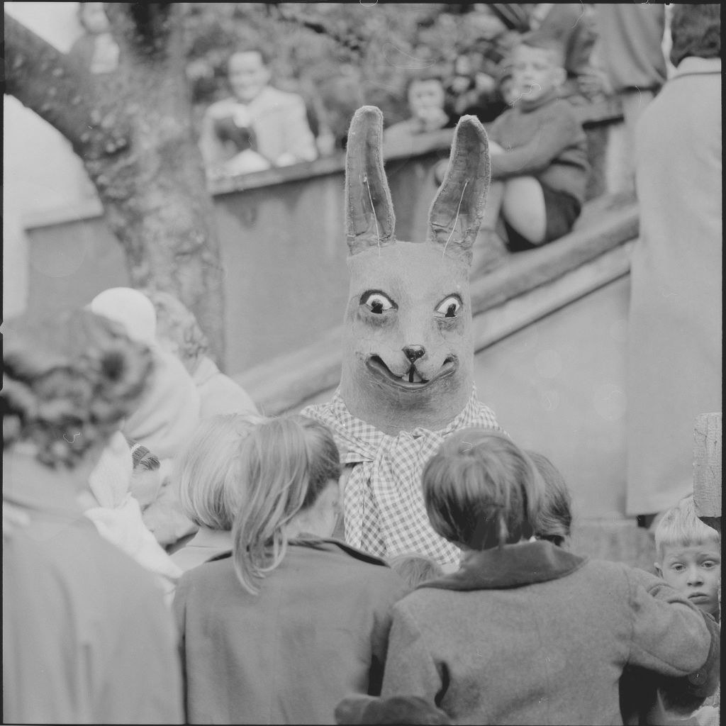 A person wearing a scary bunny costume with menacing eyes stands in front of a group of kids