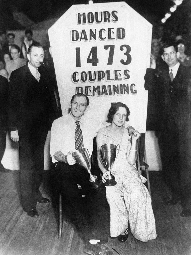 A couple sitting and holding awards