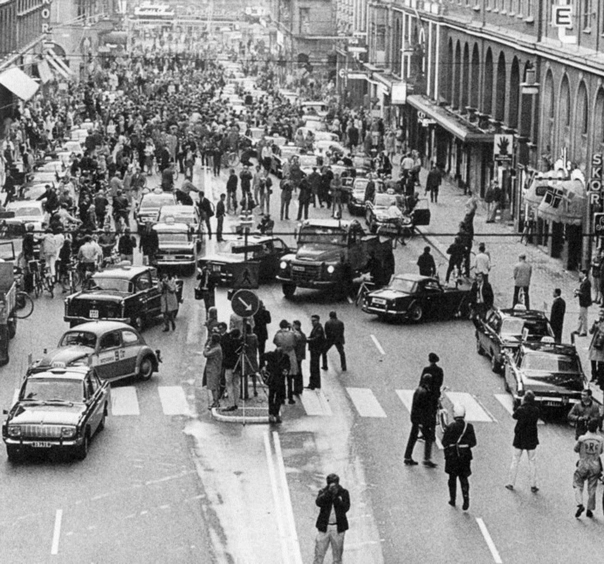 A chaotic-looking street scene with cars and people all over the street