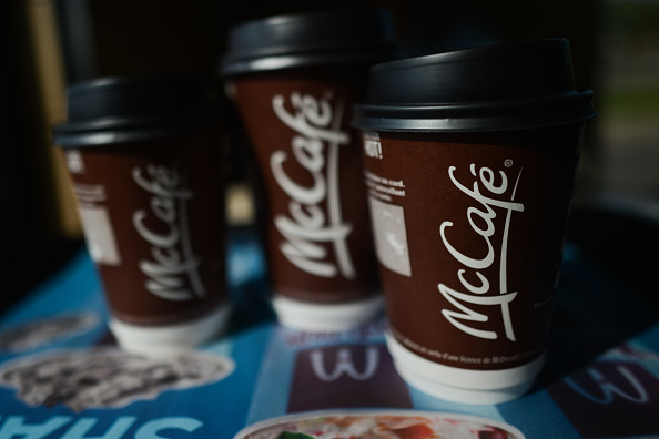 Three McCafé coffee cups placed on a table with part of a McDonald&#x27;s menu visible underneath