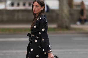 Woman in polka dot overcoat and heels crossing the street, carrying a matching polka dot handbag. I don't know who she is