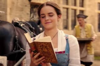 Emma Watson walking down the street and reading a bok as Belle in the live action Beauty and the Beast